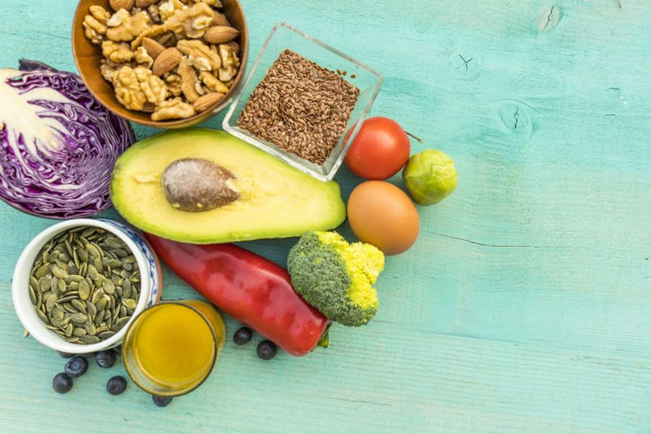 Variety of vegetables, seeds, nuts, eg, berries, avocado on green wooden table.