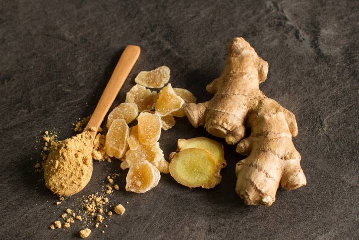 Ginger benefits for women, in whole root, powder and candy on dark table.