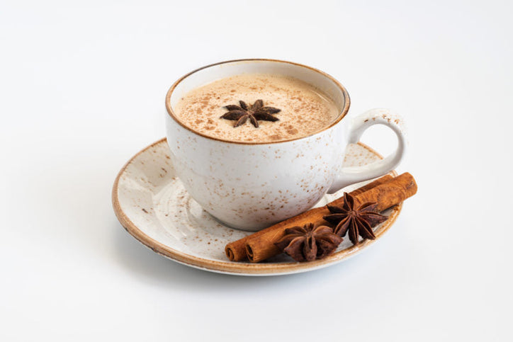 Indian Masala chai tea. Traditional Indian hot drink with milk and spices on white background close up.