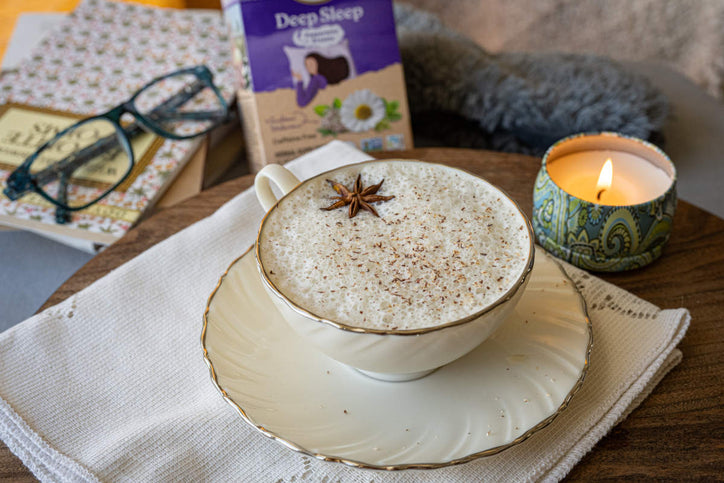 Cozy moonlit nutmeg latte with deep sleep tea in white teacup with star anise garnish and candle