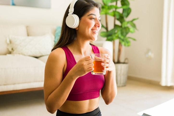 woman with headphones with herbal tea in her hands