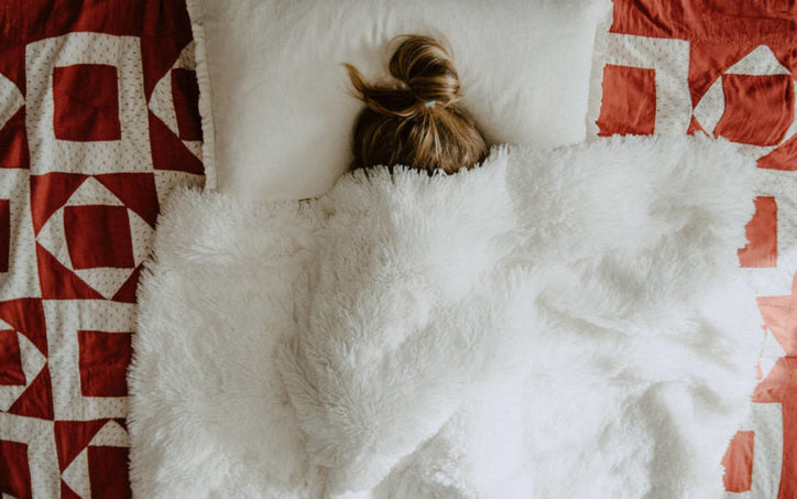 woman in a bed with blanket over her face
