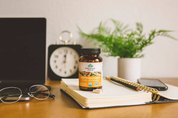 organic india capsule on atable on a notebook with a table clock in the background