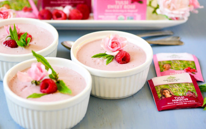 individual dessert cups filled with pink berry mousse and garnished with rose and raspberry.
