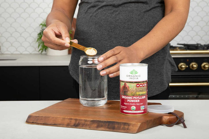 woman putting psyllium powder in her water for fibermaxxing