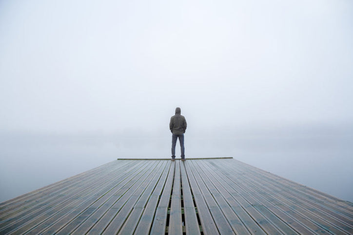 Man standing and reflecting in the power of silence on a foggy pier.