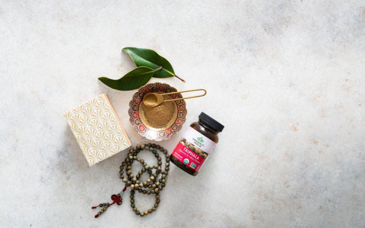 organic india triphala in a bowl with few things beside it placed aesthetically
